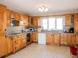 una cocina con armarios de madera y un aparato blanco en Inverbeg Cottage 1 en Downings