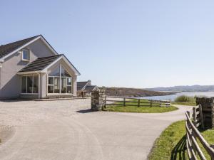 ein Haus mit Auffahrt und Zaun in der Unterkunft Inverbeg Cottage 1 in Downings