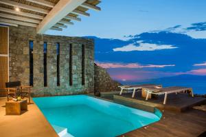 a villa with a swimming pool and a table at KLIDON Dreamy Living Suites in Mýkonos City