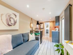 a living room with a blue couch and a kitchen at Vitamin Sea Residency in Herne Bay