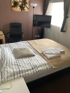 a bedroom with a bed with a chair and a television at LIMEHOUSE upon THAMES ROOM IN Great location in London