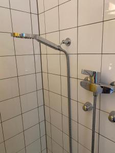 a shower with a hose in a white tiled bathroom at Apartment in Bern city centre in Bern