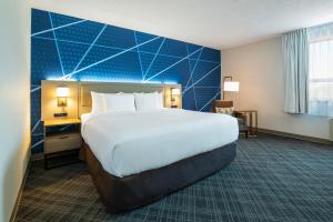 1 dormitorio con 1 cama grande y pared azul en Comfort Inn & Suites Barrie, en Barrie