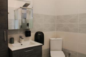 ein Badezimmer mit einem WC, einem Waschbecken und einem Spiegel in der Unterkunft Wave Luxury Apartments in Kassiopi