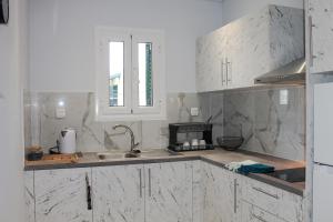 een keuken met witte marmeren werkbladen en een wastafel bij Wave Luxury Apartments in Kassiopi