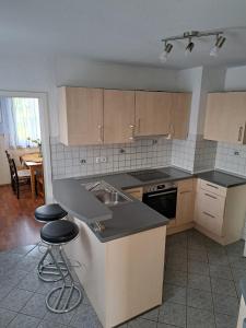 een keuken met een wastafel en een aanrecht met 2 krukken bij Gästehaus Six Inn mit Gemeinschaftsküche bis 6 Personen in Uttenweiler
