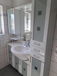 a white bathroom with a sink and a mirror at Gästehaus Six Inn mit Gemeinschaftsküche bis 6 Personen in Uttenweiler