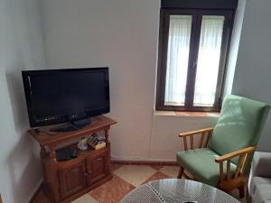 a living room with a flat screen tv and a chair at CASA ORIOL in Ayamonte