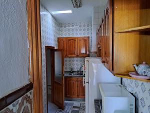 a small kitchen with wooden cabinets and a white refrigerator at CASA ORIOL in Ayamonte