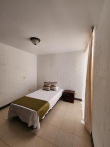 1 dormitorio con 1 cama en una habitación blanca en Jardines de Santa Maria, en Cartago
