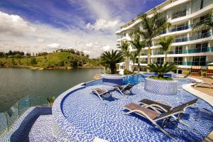 a swimming pool with chairs and a body of water at Hotel Los Recuerdos in Guatapé