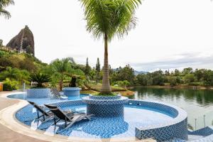 a pool with chairs and a palm tree next to a lake at Hotel Los Recuerdos in Guatapé
