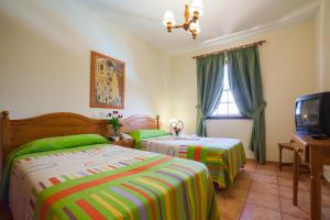 a hotel room with two beds and a television at Apartamentos Oasis San Antonio in Los Cancajos