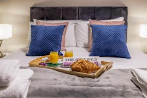 a tray of croissants and orange juice on a bed at Luxury apartment 5 min to city centre*free parking in Newcastle upon Tyne