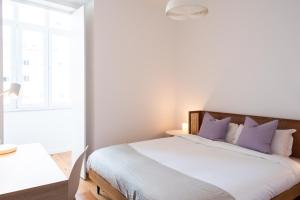um quarto com uma cama grande e almofadas roxas em Amaro II - Sleek 2 bedroom apartment in Alcantara em Lisboa