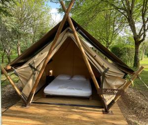 a bed in a teepee tent in the woods at Camping Le Canoë in Chaussin