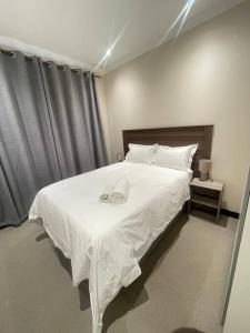 une chambre avec un grand lit blanc avec des draps blancs dans l'établissement Priceless Cove. Garden Cottage, à Midrand