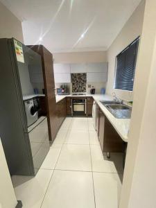 une petite cuisine avec un évier et un réfrigérateur dans l'établissement Priceless Cove. Garden Cottage, à Midrand