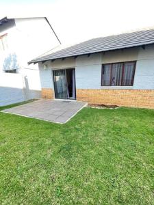 une maison avec une cour d'herbe devant elle dans l'établissement Priceless Cove. Garden Cottage, à Midrand