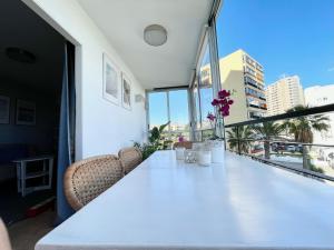 Biały stół z krzesłami i kwiatami na balkonie w obiekcie Beachfront apartment with ocean views w mieście Los Cristianos