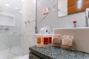 uma casa de banho com lavatório e produtos de higiene pessoal no balcão em Pousada La Toscana Campos do Jordão em Campos do Jordão