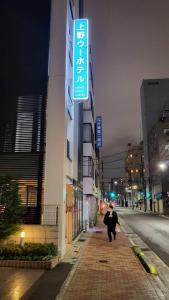 a person walking down a street next to a building at Ueno Woo Hotel in Tokyo