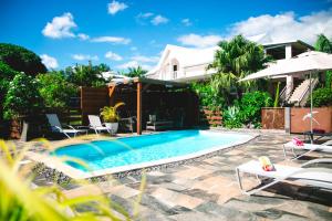 a swimming pool with chairs and a house at LE COLONIAL, T4 à 5 mn Aeroport dans villa de standing in Sainte-Marie