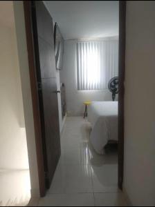 um quarto com uma cama branca e uma janela em Bright Duplex 2 bedroom Apartment, kitchen, bathroom & living room em Cartagena de Indias