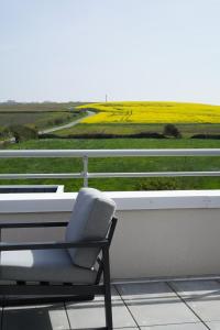 a chair sitting on a balcony with a view of a field at Le Wim' - Appart neuf proche plage et centre ville in Wimille