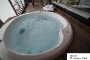 La salle de bains est pourvue d'une baignoire remplie d'eau bleue. dans l'établissement Kuranoya Furano, à Furano