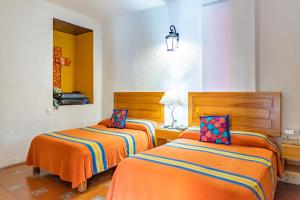 two beds in a room with orange sheets at Hotel Posada del Centro in Oaxaca City