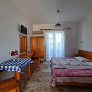 a bedroom with two beds and a table and a television at Studio Bellos in Tolo