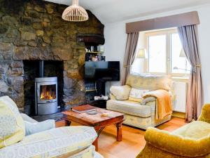 a living room with a stone fireplace and a couch and chair at Rose Cottage in Kirkton of Glenbuchat