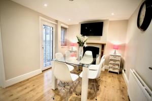 a dining room with a glass table and white chairs at Mill House Townhouse in Newmarket