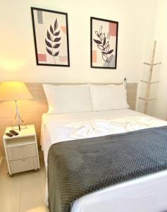 een slaapkamer met een bed en drie foto's aan de muur bij Apto Bella Citta em Cabo Frio in Cabo Frio