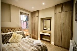 1 dormitorio con cama, tocador y espejo en Mill House Townhouse, en Newmarket
