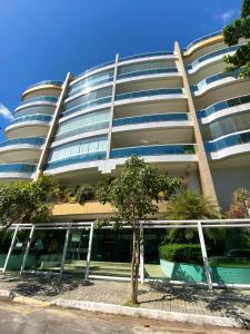 un edificio con un árbol delante de él en Apto Bella Citta em Cabo Frio, en Cabo Frío