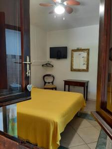 a bedroom with a yellow bed and a ceiling fan at casa di campagna dal pozzo in Sorso
