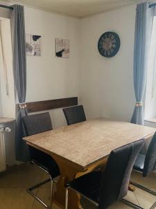 a dining room table with chairs and a clock on the wall at Ferienwohnung Burkhart in Bundenthal