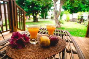two glasses of orange juice and fruit on a table at Villa Le Colonial Zen - T4 à 5 mn Aéroport in Sainte-Marie