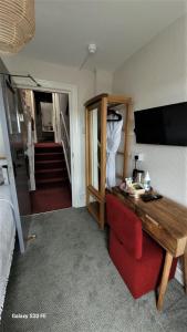 a room with a bed and a desk and a television at Greylands Guest House in Llandrindod Wells