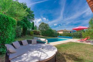 un patio trasero con mesa, sombrilla y piscina en Villa 80m² 3ch Piscine, en Fayence