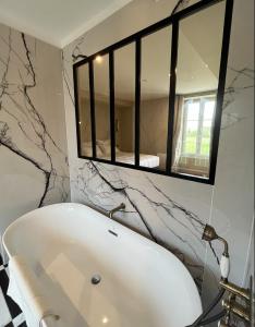La salle de bains est pourvue d'une baignoire blanche et d'un miroir. dans l'établissement DOMAINE DU GRAND CAUGY, à Saint-Vigor-le-Grand