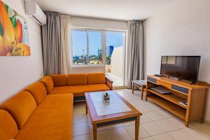een woonkamer met een bank en een tv bij The House of Nonni Ventura - beachfront, ocean view, Wi-Fi, aircon, swimming pool in Morro del Jable