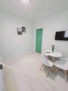 Pokój ze stołem, 2 krzesłami i zielonymi drzwiami w obiekcie Appartement proche St denis "appart 3" w mieście Pierrefitte-sur-Seine