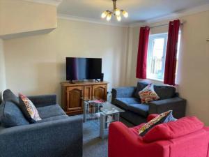 a living room with two couches and a flat screen tv at Exclusive Homely Cambridge 4 bed house with free parking, big garden and sleeps 10 in Cambridge