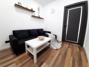 a living room with a black couch and a white table at Modern Apartment Near Airport in Chişinău