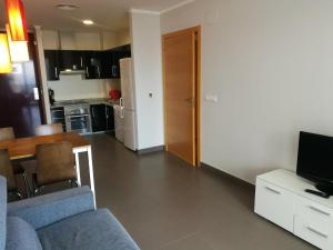 a living room with a couch and a television and a kitchen at Aparthotel El Faro in Cullera