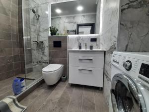 a bathroom with a toilet and a washing machine at Modern Apartment Near Airport in Chişinău