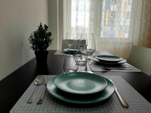a table with green plates and silverware on it at Modern Apartment Near Airport in Chişinău